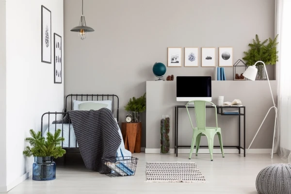 Bright grey bedroom interior with workspace that has a desk and computer