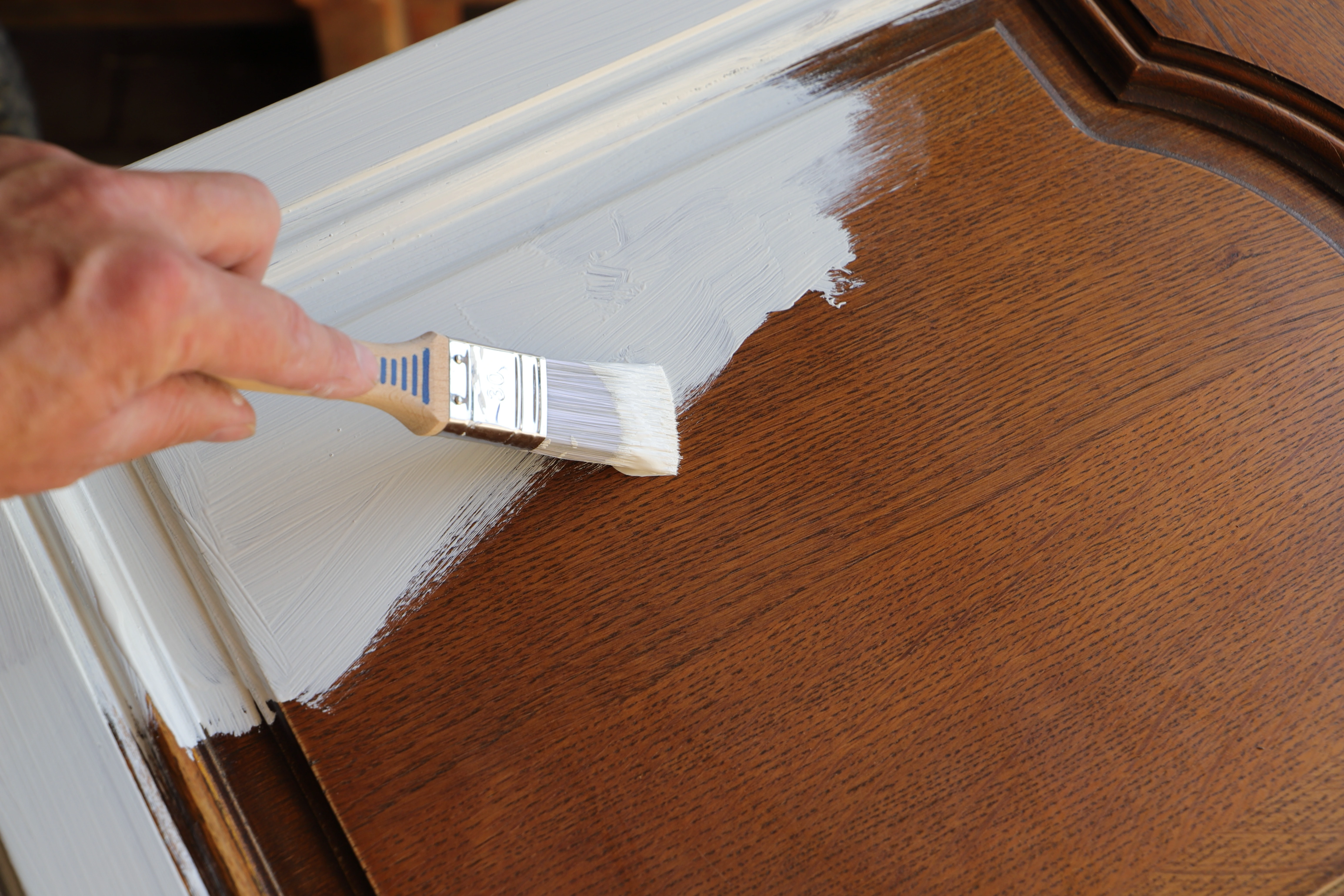 Brown cabinet door being painted white.