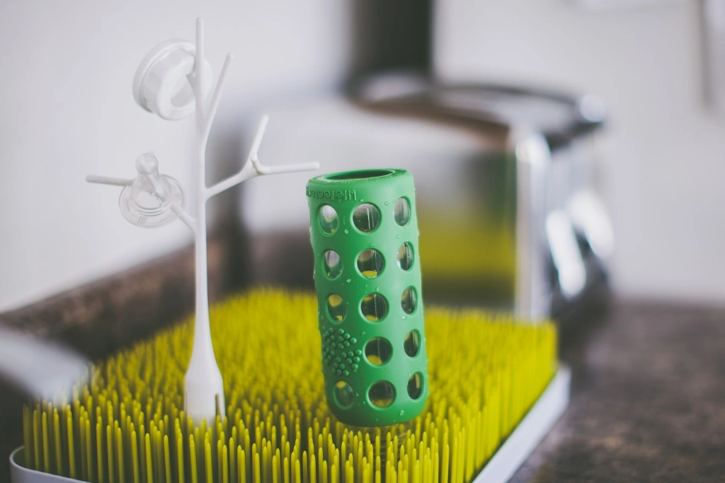 Special baby bottle drying rack on kitchen countertop with bottle pieces drying on it