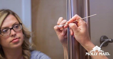 Woman cleaning a bathroom mirror with a cotton swab