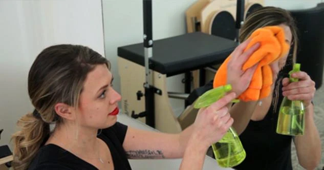 A woman spray-cleaning a mirror in a home gym