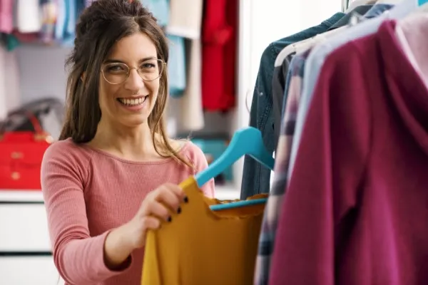 Woman hanging up clothes in her bedroom closet