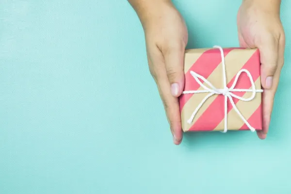 Hands holding craft paper gift box.