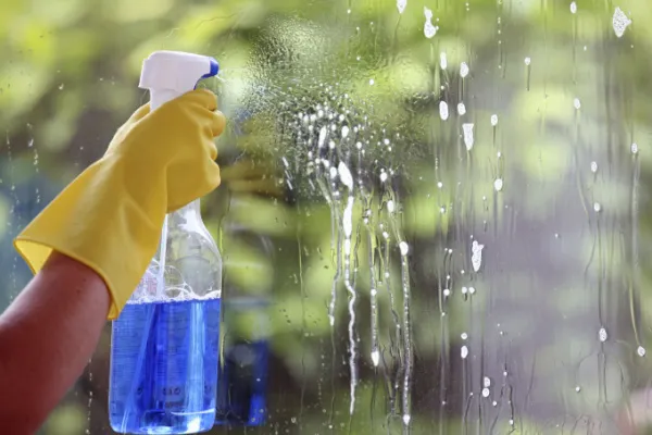 Person spraying cleaning solution on a window