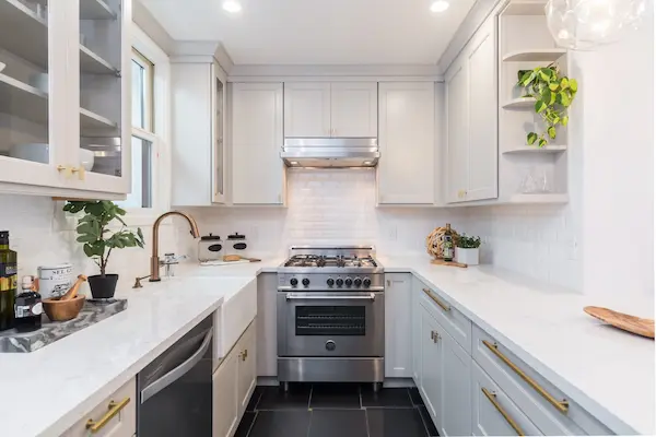 Bright, white modern kitchen with stainless steel stove.