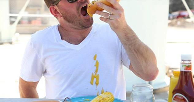 man spilling mustard down front of his white shirt