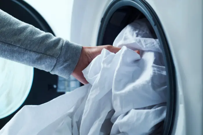 Person putting bedding into washing machine