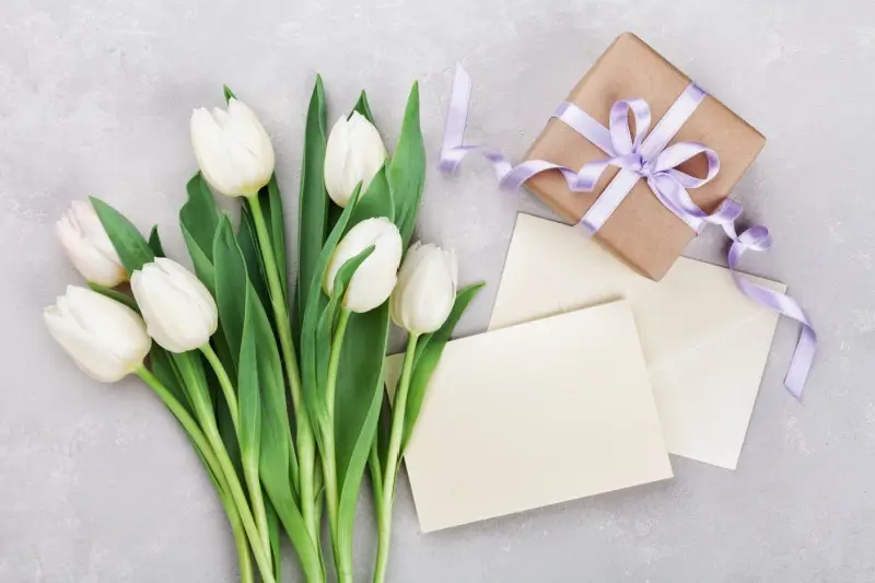 Flowers, cards, and a gift on a table for Mother's Day. 