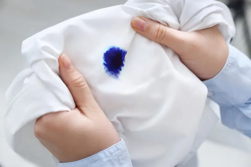 Person holding white shirt with blue Sharpie stain.