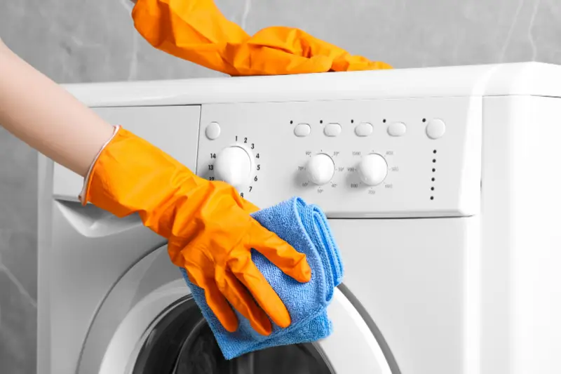 Person cleaning the outside of a washing machine