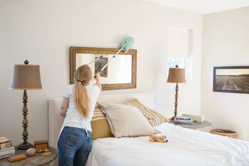 Woman dusting her bedroom