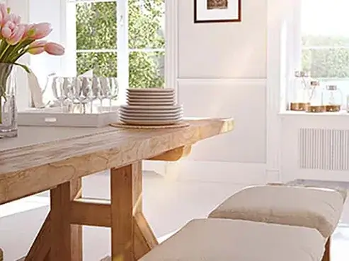 Dining room table stacked with dishes beside tray of wine glasses.